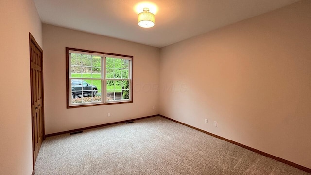 empty room with light colored carpet, baseboards, and visible vents
