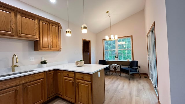 kitchen featuring brown cabinetry, a sink, light wood-style floors, and a peninsula
