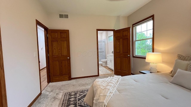 bedroom with carpet floors, baseboards, visible vents, and ensuite bathroom