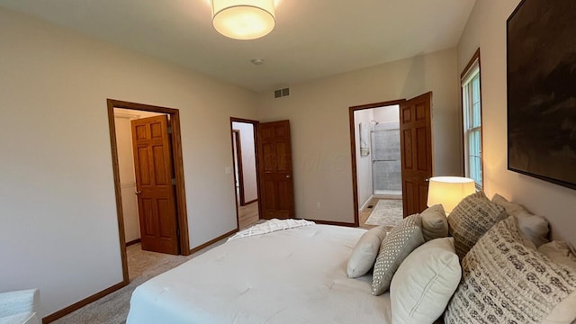 bedroom with baseboards, visible vents, light carpet, and ensuite bath
