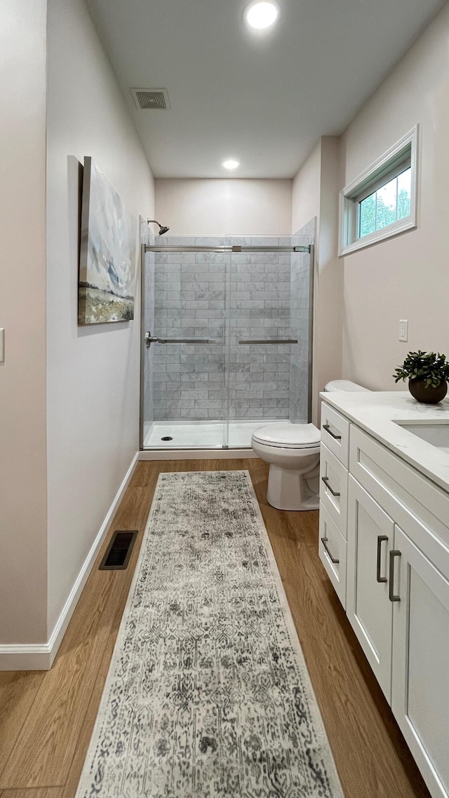 full bath featuring visible vents, a stall shower, toilet, and wood finished floors