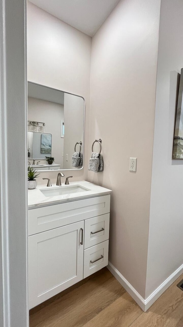 bathroom featuring baseboards, wood finished floors, and vanity