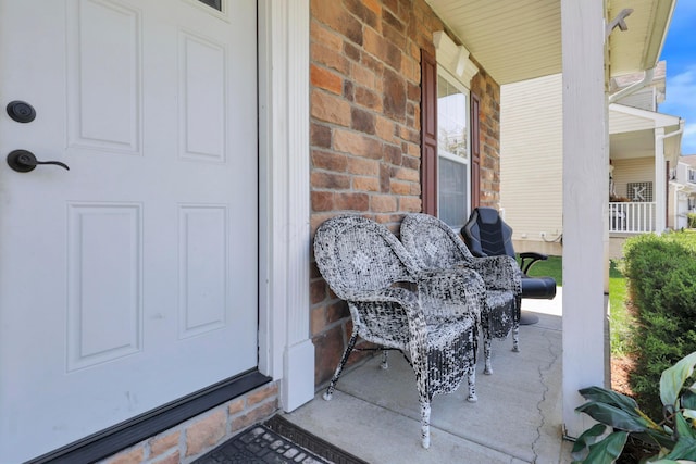 doorway to property with brick siding and a porch