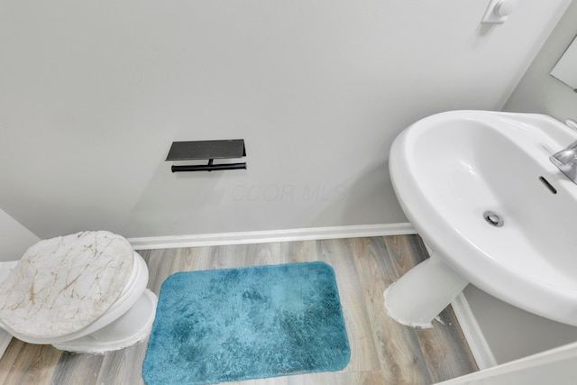 bathroom with baseboards, wood finished floors, and a sink