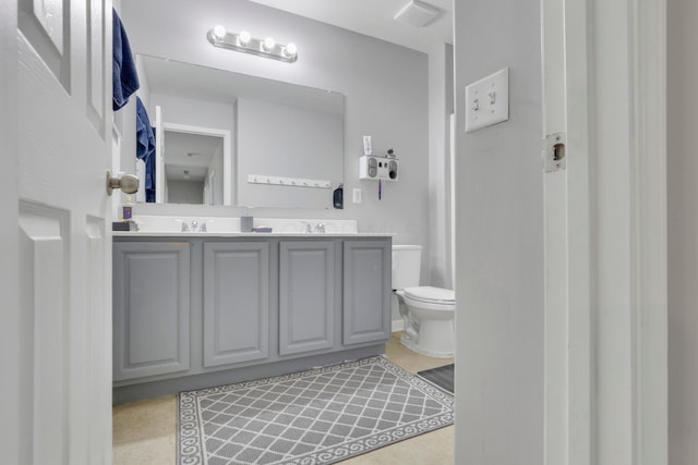 full bath with toilet, double vanity, and a sink