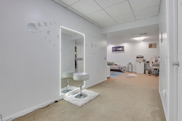 corridor featuring carpet flooring, baseboards, a drop ceiling, and visible vents