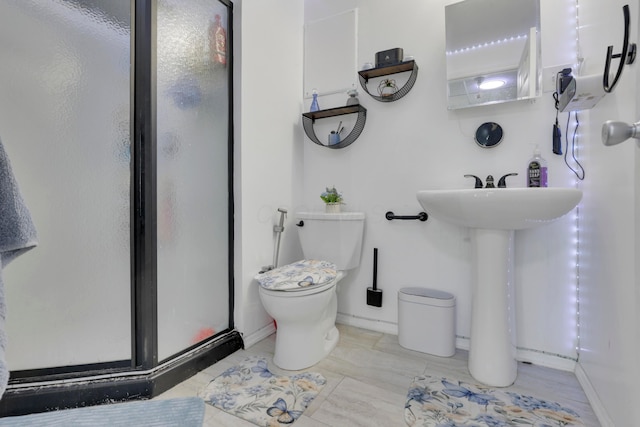 bathroom with toilet, a sink, a shower stall, and baseboards