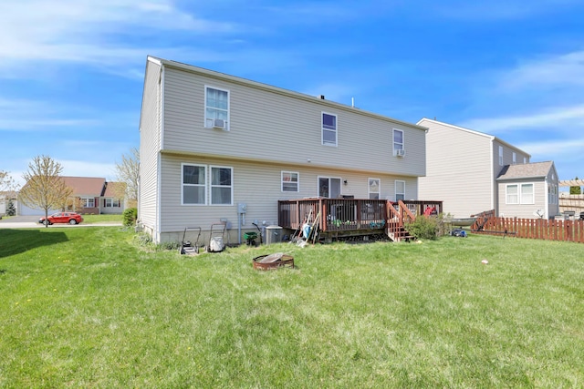 rear view of house with a lawn, a wooden deck, and fence