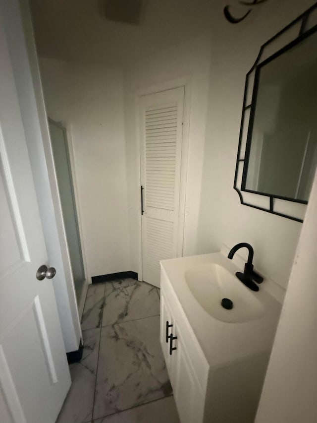 bathroom with marble finish floor, vanity, and baseboards