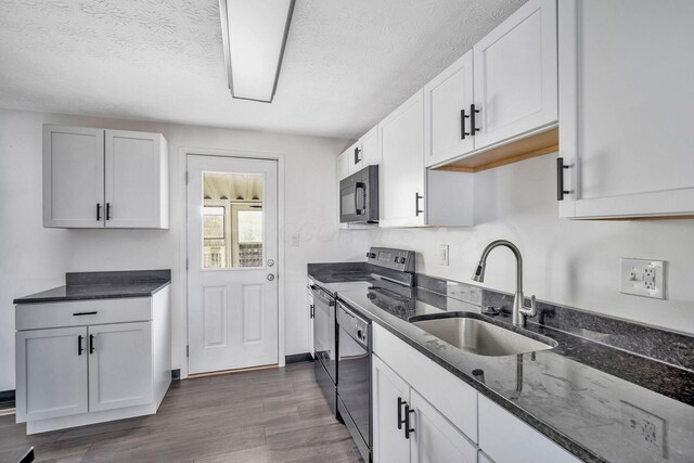 2987 Olivette Rd, Columbus, OH 43232 - kitchen featuring a sink, range with electric cooktop, black microwave, dark stone counters, and dark wood-style floors