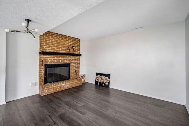 2987 Olivette Rd, Columbus, OH 43232 - unfurnished living room with wood finished floors, a chandelier, a brick fireplace, baseboards, and a textured ceiling