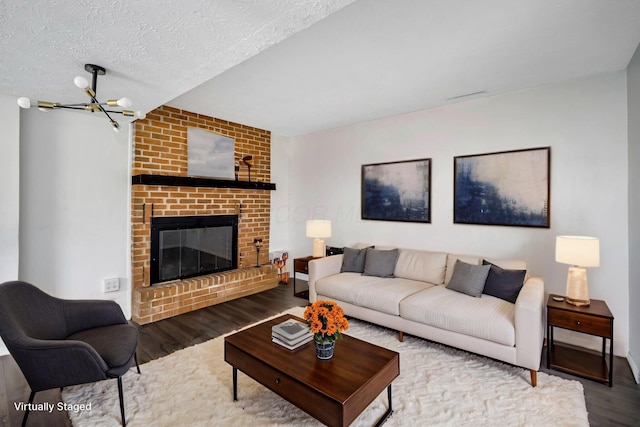 2987 Olivette Rd, Columbus, OH 43232 - living area featuring wood finished floors, a chandelier, a fireplace, and a textured ceiling