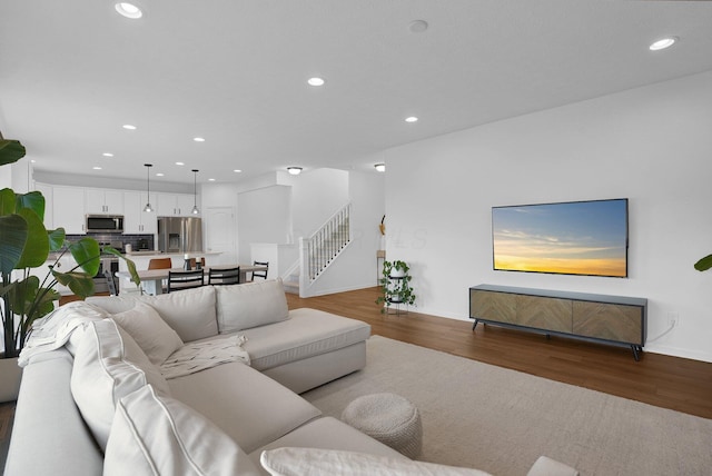 living area featuring stairs, recessed lighting, baseboards, and wood finished floors