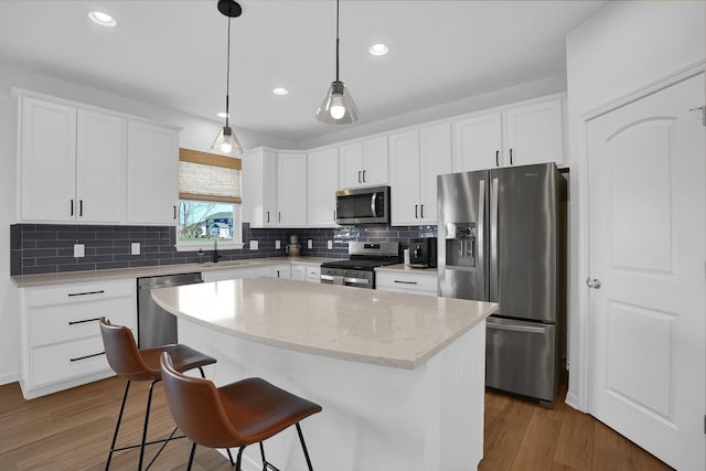 kitchen featuring a center island, appliances with stainless steel finishes, wood finished floors, and a kitchen bar