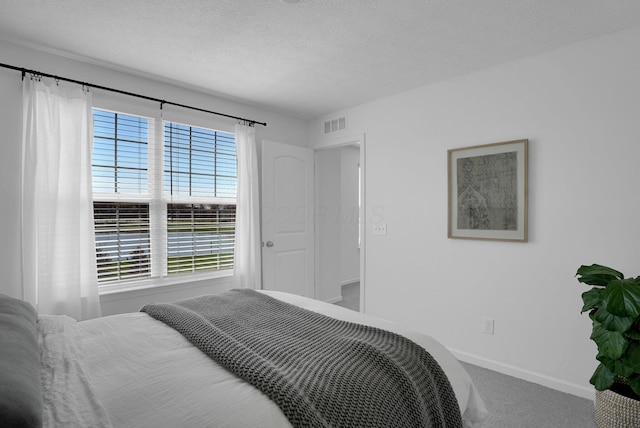 bedroom with carpet floors, a textured ceiling, baseboards, and visible vents