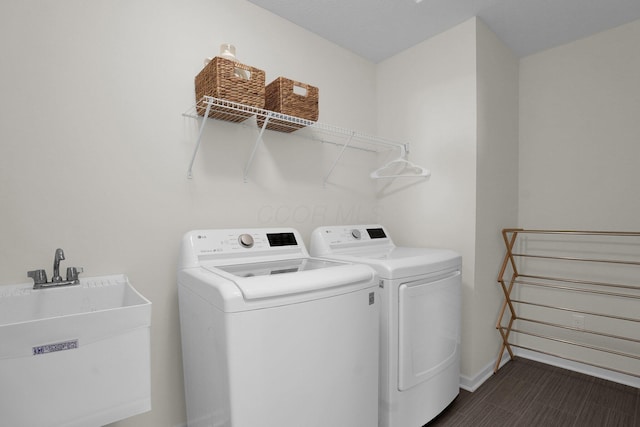 clothes washing area with laundry area, a sink, baseboards, and separate washer and dryer