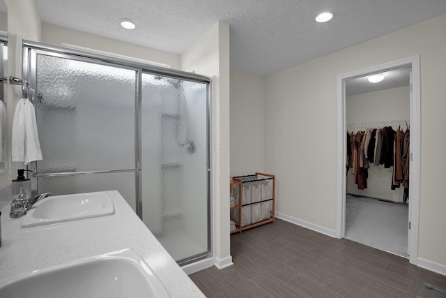 full bath with a sink, baseboards, a shower stall, and a spacious closet