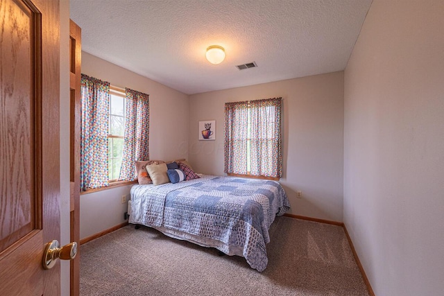 carpeted bedroom featuring a textured ceiling, baseboards, and visible vents
