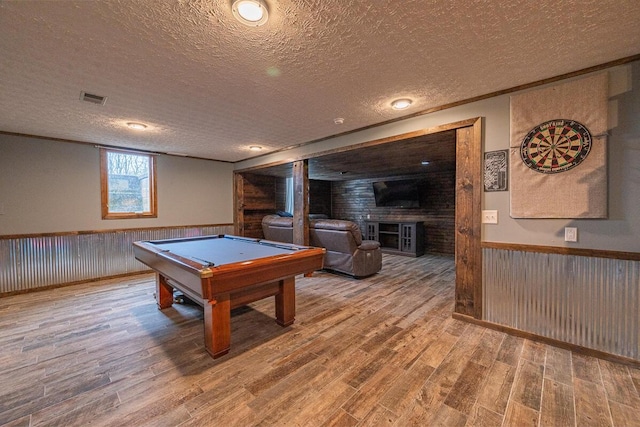 rec room with a wainscoted wall, a textured ceiling, and visible vents