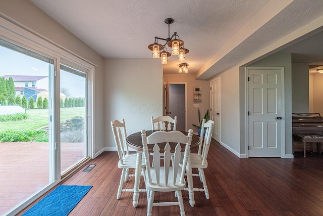 dining space featuring hardwood / wood-style floors, a textured ceiling, visible vents, an inviting chandelier, and baseboards