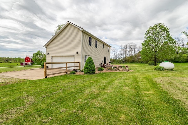 view of side of property featuring a yard, an attached garage, and driveway