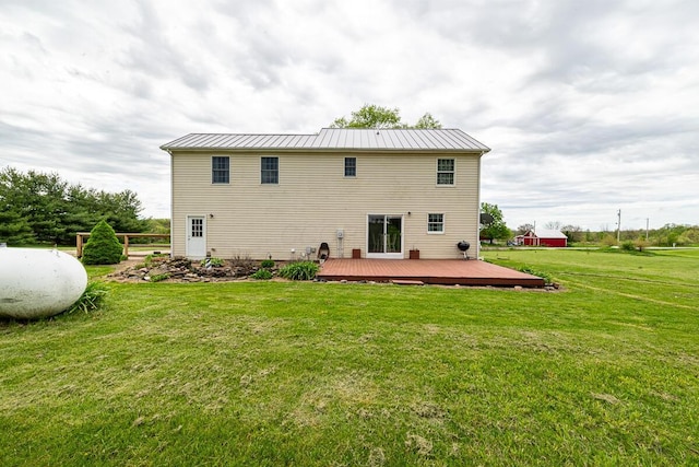 rear view of property featuring metal roof, a wooden deck, a standing seam roof, and a lawn
