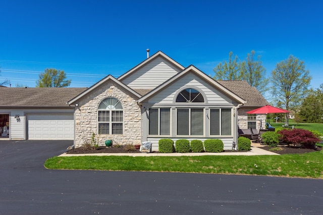 view of front of home with a garage, driveway, and stone siding