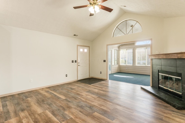 unfurnished living room with ceiling fan, visible vents, a tile fireplace, wood finished floors, and high vaulted ceiling