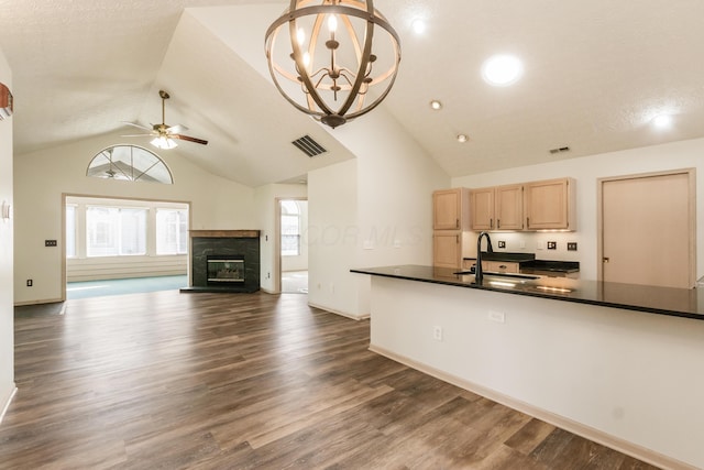 kitchen with visible vents, light brown cabinetry, dark countertops, a sink, and ceiling fan with notable chandelier