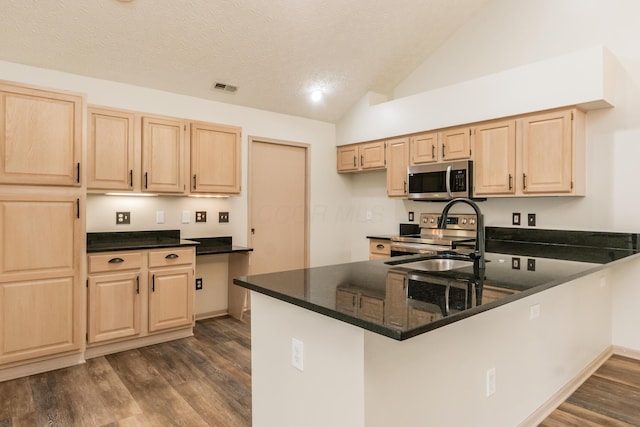 kitchen with appliances with stainless steel finishes, light brown cabinets, dark wood finished floors, a peninsula, and visible vents