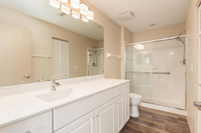 full bath with vanity, a stall shower, wood finished floors, and toilet