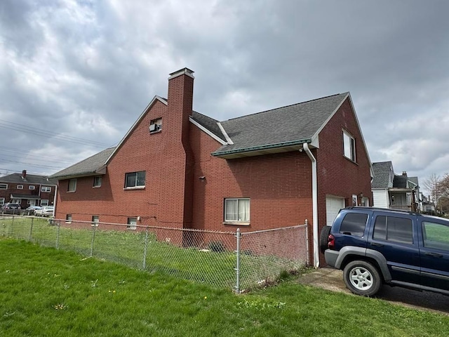 view of home's exterior with a lawn, fence, a chimney, brick siding, and an attached garage