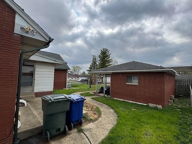 view of side of property featuring a lawn, brick siding, and a shingled roof
