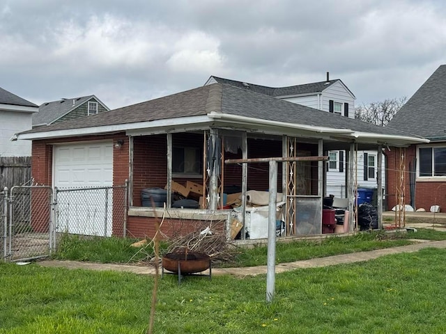 rear view of property with a lawn, brick siding, fence, and a garage