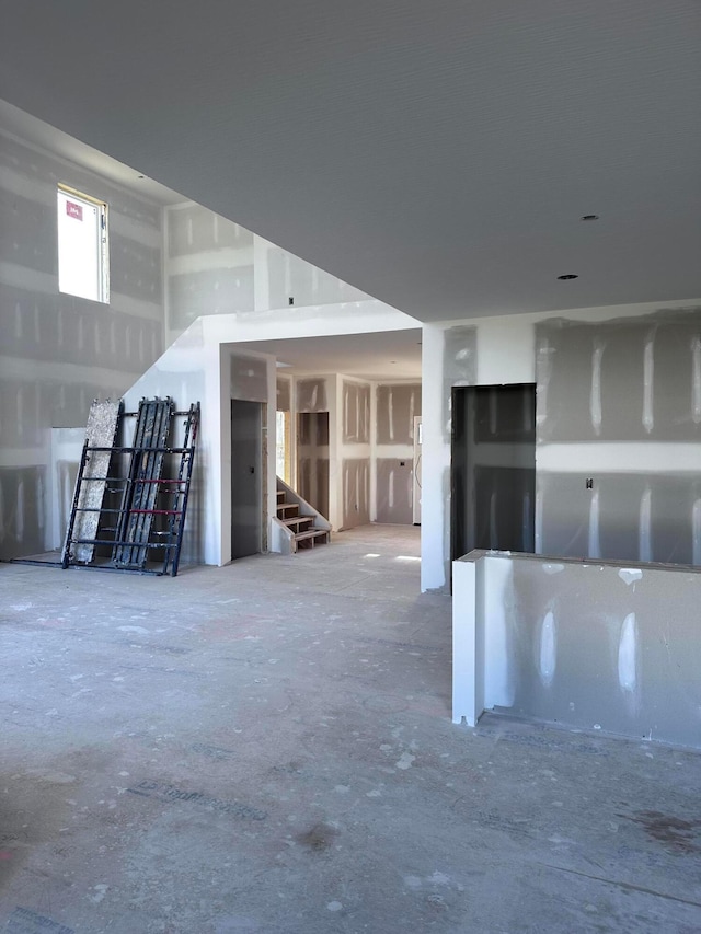 unfurnished living room featuring concrete floors and stairs