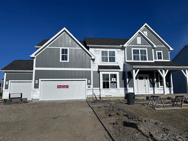 view of front of house with board and batten siding, driveway, and roof with shingles