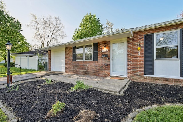 view of front of home featuring brick siding, driveway, fence, and a garage