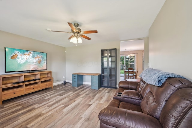 living room with baseboards, light wood finished floors, and ceiling fan with notable chandelier