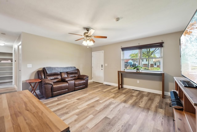 living area with baseboards, ceiling fan, and wood finished floors