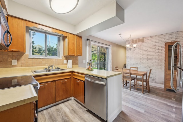 kitchen featuring appliances with stainless steel finishes, a sink, brown cabinetry, light wood-style flooring, and visible vents