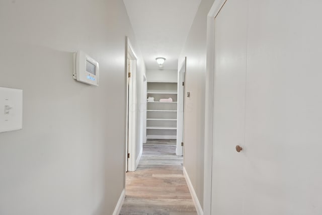 hall with baseboards and light wood-type flooring