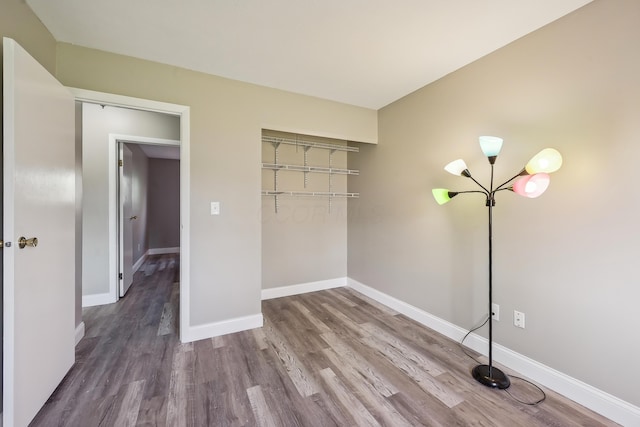 unfurnished bedroom with baseboards, wood finished floors, and a closet