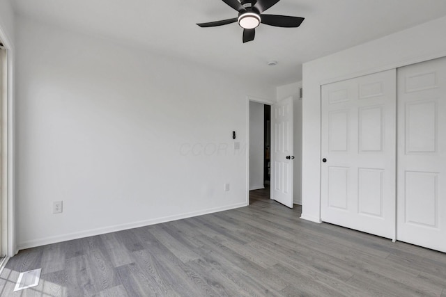 unfurnished bedroom with visible vents, ceiling fan, wood finished floors, and baseboards