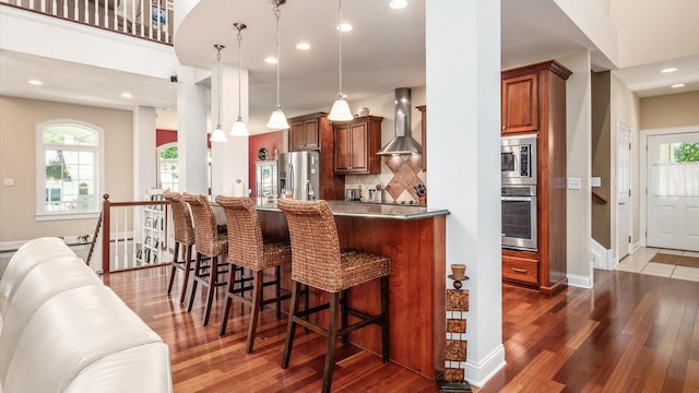 87 Dartmouth Rd SE, Hebron, OH 43025 - kitchen featuring recessed lighting, stainless steel appliances, wall chimney exhaust hood, a breakfast bar area, and wood finished floors