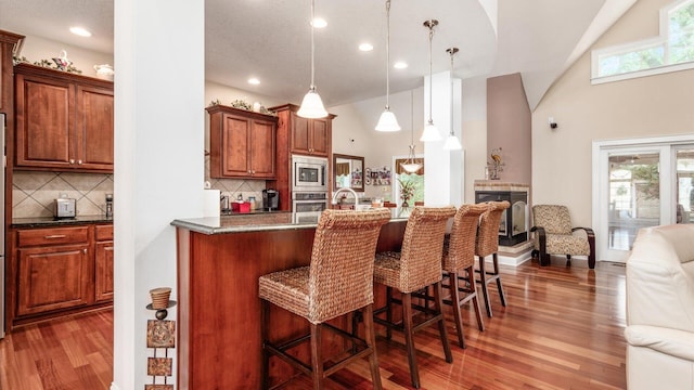 87 Dartmouth Rd SE, Hebron, OH 43025 - kitchen featuring stainless steel appliances, a breakfast bar, open floor plan, backsplash, and wood finished floors