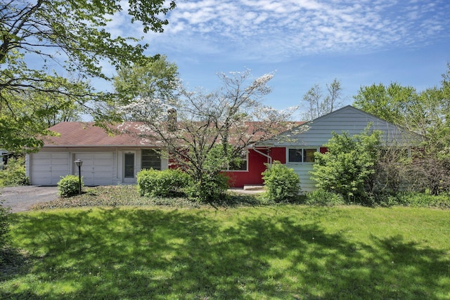 view of front of home with a chimney, an attached garage, a front yard, and aphalt driveway