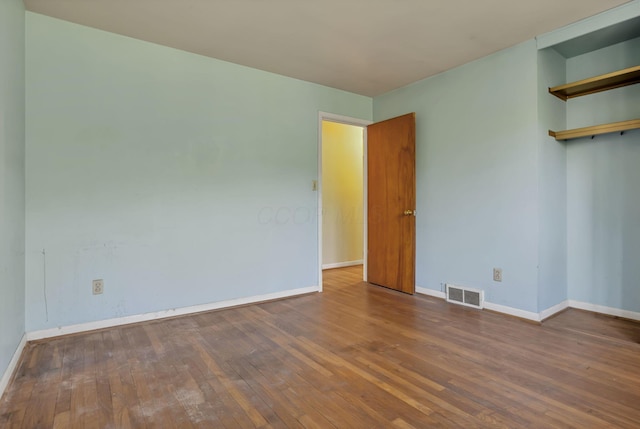 empty room featuring baseboards, hardwood / wood-style flooring, and visible vents