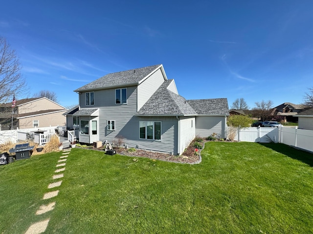 back of property with a lawn, roof with shingles, and fence