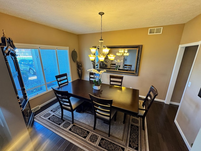 dining room with an inviting chandelier, visible vents, wood finished floors, and a textured ceiling