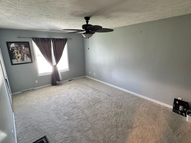spare room featuring a ceiling fan, visible vents, carpet, baseboards, and a textured ceiling